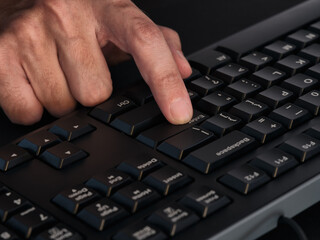 A person pressing the enter key on a black keyboard