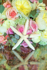 Closeup of bridal bouquet with wedding rings on starfish.