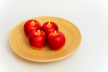 The wicks of candles in the form of apples in a plate are burning