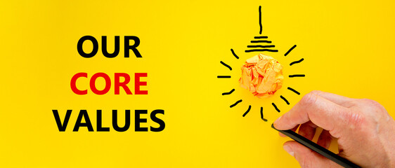 Our core values symbol. Businessman writing words 'Our core values', isolated on beautiful yellow...