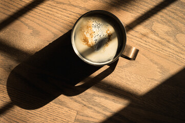 Cup of Coffee Sitting on Sunny Wooden Surface with Strong Shadows