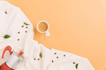 Coffee pot and coffee cup with beans and green leaves. Creative flat lay.