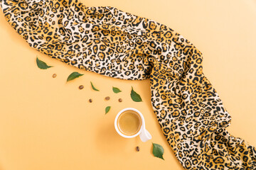 Black espresso coffee in a cup with leaves and coffee beans. Leopard wild animal print scarf.