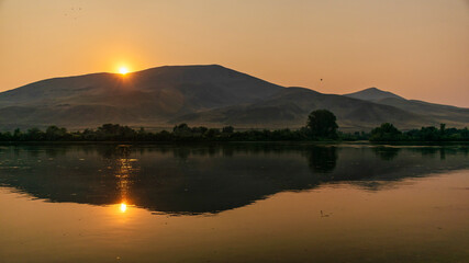 sunset over a river with mountains