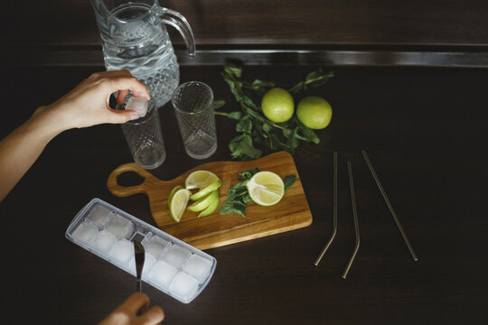Top view of woman's hand puts an ice cube in a glass for mojito