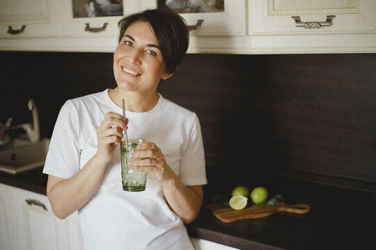 Smiling woman drinks non-alcoholic cocktail with reusable steel straw