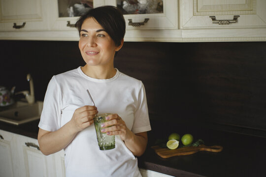 View of smiling woman drinks nonalcoholic cocktail with reusable straw