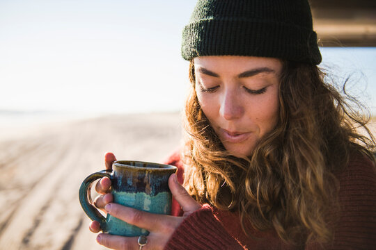 Young woman enjoying cup of coffee in the morning beach car camping