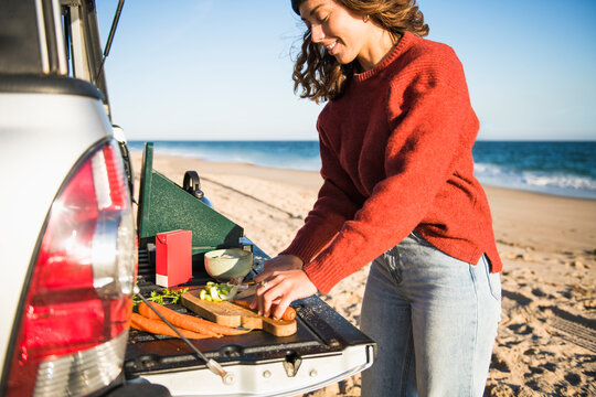 Young woman tailgating cooking while beach car camping alone