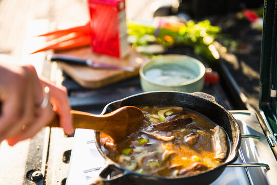 Young woman tailgating cooking while beach car camping alone
