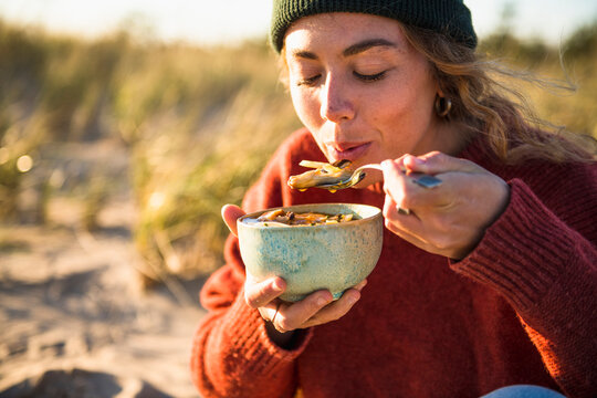Young woman enjoying soup while beach car camping alone