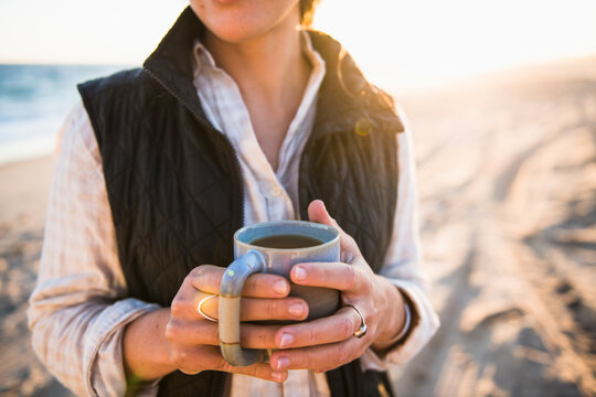 Young woman holding mug while beach car camping alone