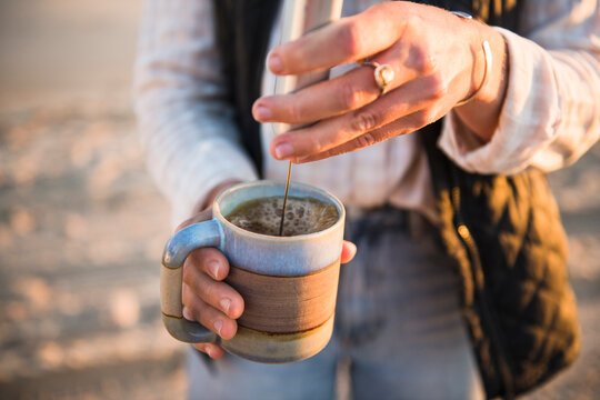Young woman emulsifying coffee while beach car camping