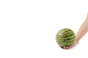 The hand holds a small watermelon on a white background. Summer fruits and refreshments. Minimal summer food concept.