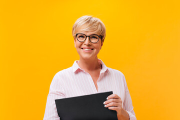 Happy lady in eyeglasses and pink shirt smiling on orange background