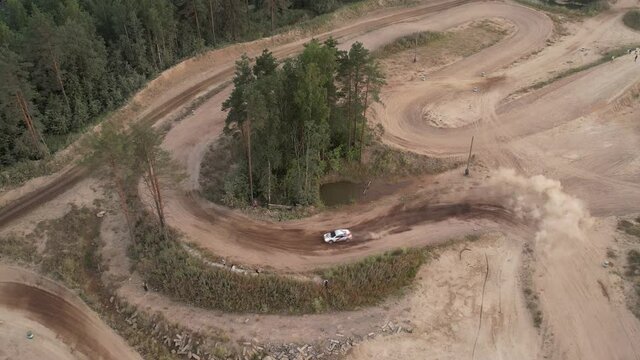 Aerial footage of a car race car driving into a drift on a dusty road.