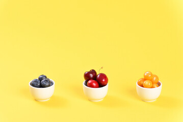 Berries assorted cherry, physalis and blueberries in small bowls.