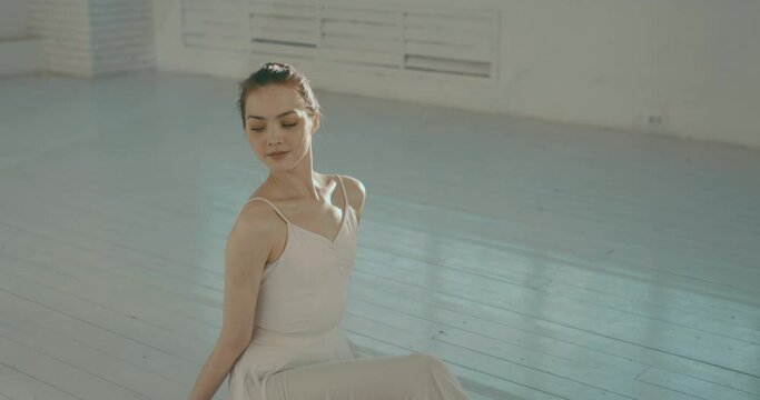 Portrait shot of young female ballerina in dancing studio, looking at camera and smiling. Model posing for a photo shoot - real people 4k footage