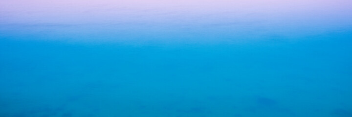 Abstract Seascape Blue and Pink Background Photo. Blurred Ocean and Rising Sun Rays on a Foggy Morning. Soft Pastel Space for Text and Design.