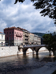 Obraz premium Peek to the Latin Bridge, through some trees, over the Miljacka river. Sarajevo, Bosnia and Herzegovina.