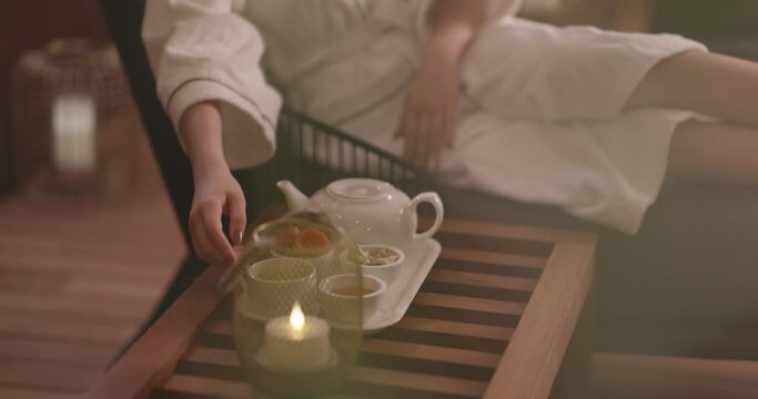 Mindful asian girl in white robe relaxing in oriental spa resort, drinking tea. Elegant woman relaxing, finding inner peace and balance - wellbeing 4k footage