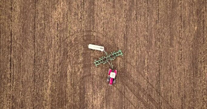 Aerial view of a tractor pulling a plow and an anhydrous tank of ammonia in a farmer's field. Heavy machinery during cultivation, work in the fields. Agricultural tractor in the field.