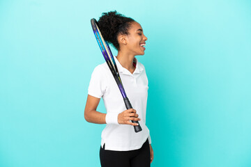 Young tennis player woman isolated on blue background laughing in lateral position