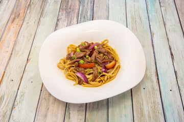 Peruvian-style sautéed noodles with striploin meat, fresh vegetables and red onion with soy sauce