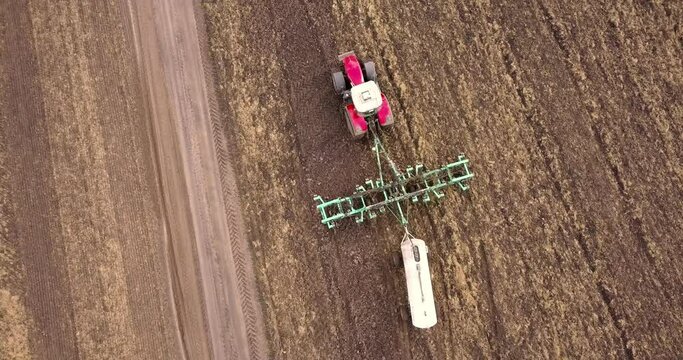 Aerial view of a tractor pulling a plow and an anhydrous tank of ammonia in a farmer's field. Heavy machinery during cultivation, work in the fields. Agricultural tractor in the field.