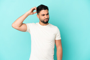Young arab man isolated on blue background having doubts while scratching head