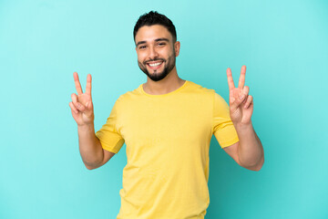 Fototapeta premium Young arab man isolated on blue background showing victory sign with both hands
