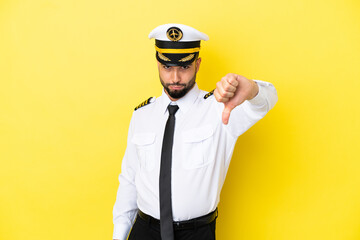 Airplane arab pilot man isolated on yellow background showing thumb down with negative expression © luismolinero