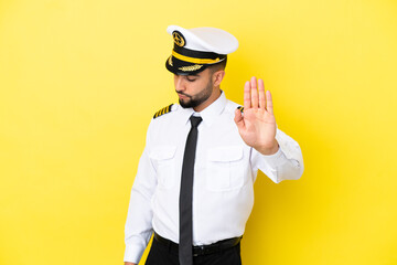 Airplane arab pilot man isolated on yellow background making stop gesture and disappointed