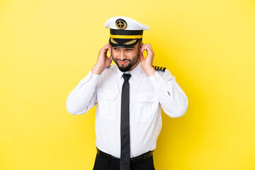 Airplane arab pilot man isolated on yellow background frustrated and covering ears © luismolinero