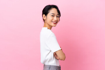 Young Vietnamese woman isolated on pink background looking to the side and smiling