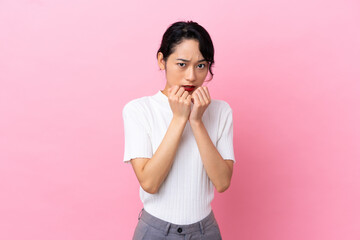 Young Vietnamese woman isolated on pink background nervous and scared putting hands to mouth