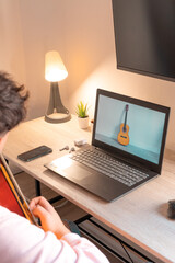 Detalle de la mesa de estudio musical con ordenador con guitarra de fondo de pantalla.