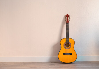 Detalle de una guitarra con fondo ocre con espacio.
