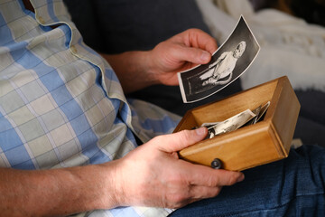 an elderly man looks through his old photographs of 1960-1965, the concept of nostalgia and...