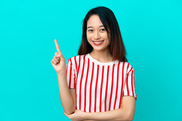 Young Vietnamese woman isolated on blue background happy and pointing up