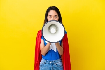 Super hero Vietnamese woman isolated  on yellow background shouting through a megaphone