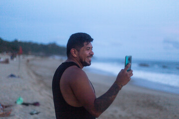 man holding his smart phone making a video call on the beach