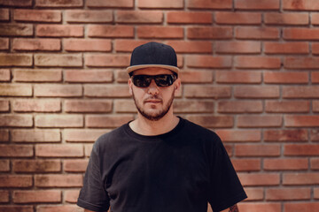 white man in cap, sunglasses and black t-shirt on neutral background