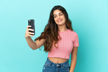 Young caucasian woman isolated on blue background making a selfie