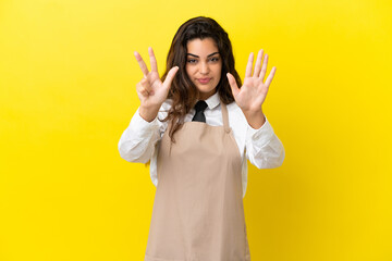 Young caucasian restaurant waiter isolated on yellow background counting eight with fingers