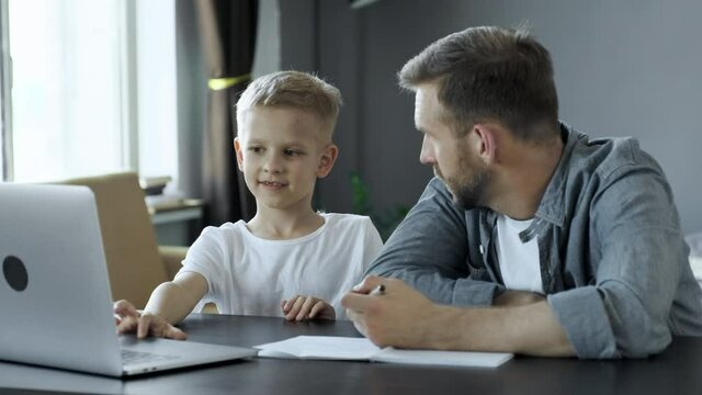Smiling son thanking father for his help in doing homework at home
