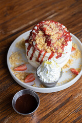 delicious sweet breakfast, pancakes with banana and strawberries, cream and chocolate, a cup of coffee