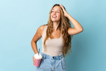 Young woman with strawberry milkshake isolated on blue background smiling a lot