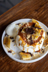 delicious sweet breakfast, pancakes with banana and strawberries, cream and chocolate, a cup of coffee