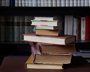 old books are stacked against the background of a bookcase